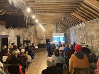 a group of people sitting in a room watching a presentation